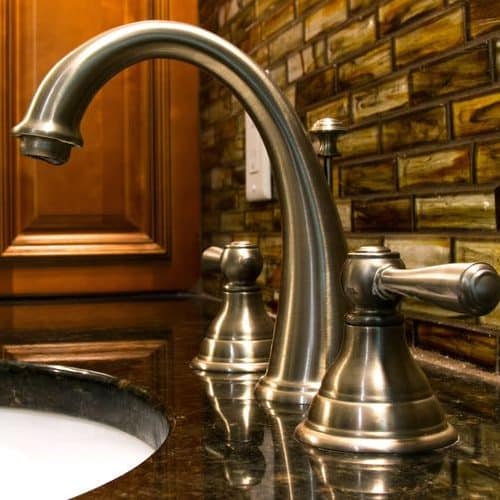 A Picture of a Faucet with a Granite Countertop Underneath it.
